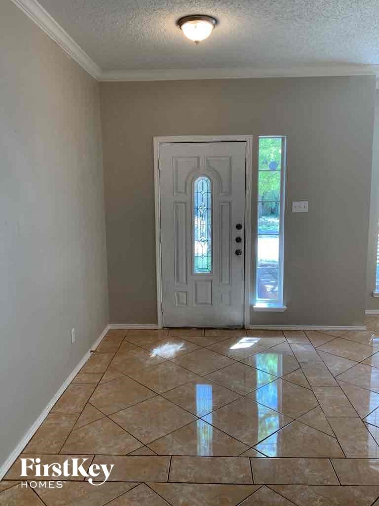 an empty living room with a white door and tiled floor