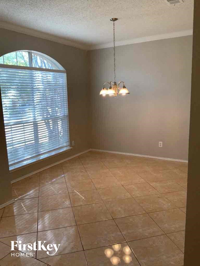 an empty dining room with a large window and a chandelier