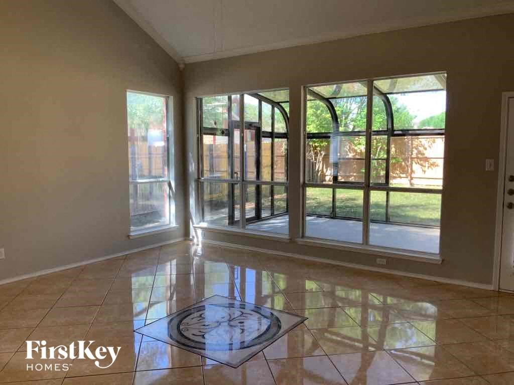 an empty living room with large windows and a tile floor