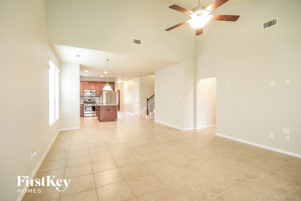 A spacious room with a fan and tiled flooring.
