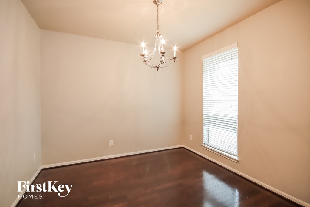 A room with a chandelier and a window with blinds.