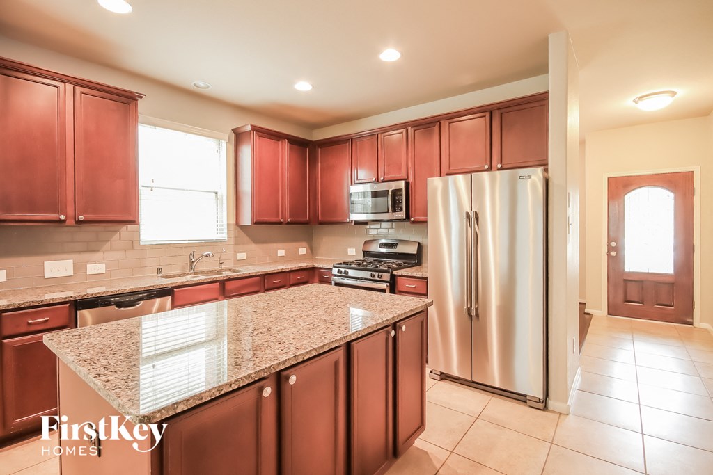 A kitchen with red cabinets and a granite countertop.