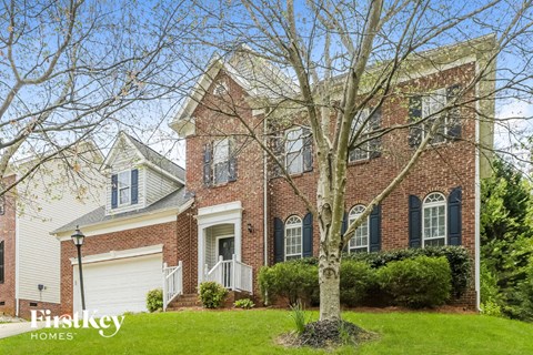 the front of a brick house with a tree in front of it