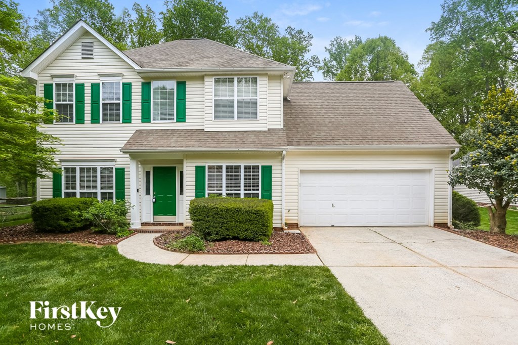 a white house with green shutters and a driveway