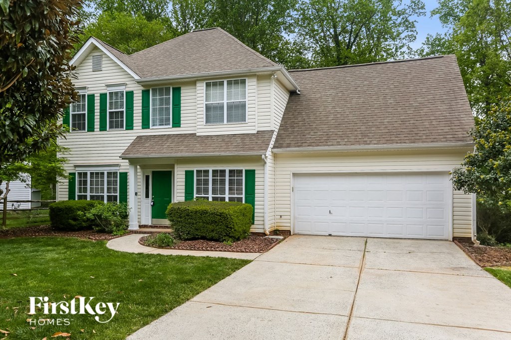 a white house with green shutters and a driveway