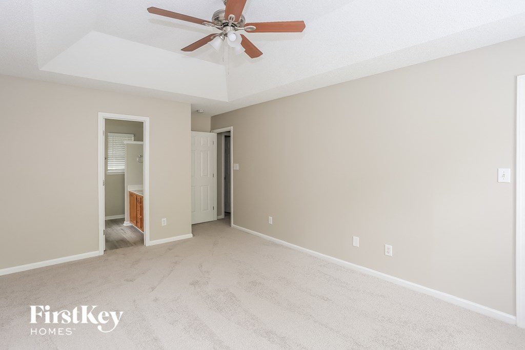 an empty living room with a ceiling fan and a white carpet