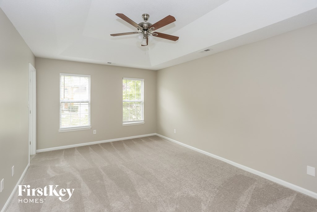 an empty living room with a ceiling fan and a carpet