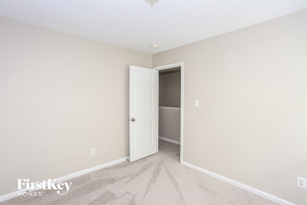 a bedroom with a white door and a hallway to a closet
