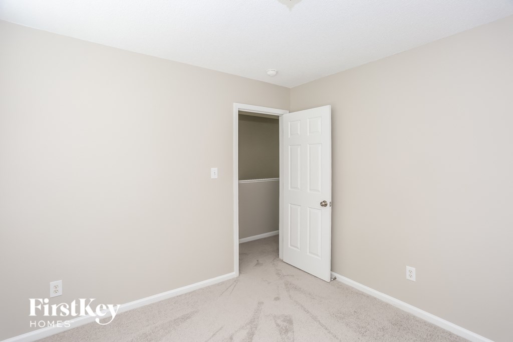 a bedroom with a white door and a hallway to a closet