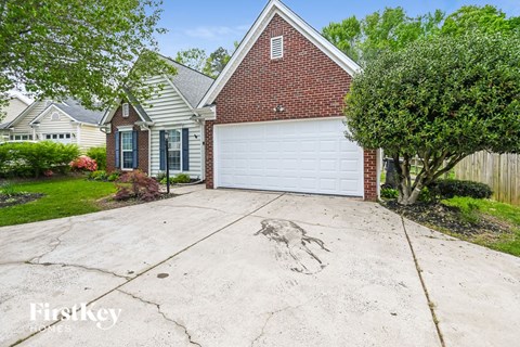 a large driveway in front of a brick house with a white garage door
