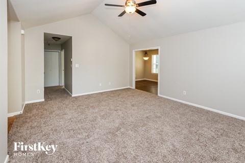 a spacious living room with carpet and a ceiling fan