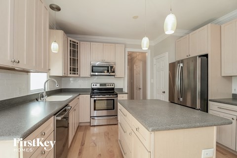 a white kitchen with stainless steel appliances and gray counter tops