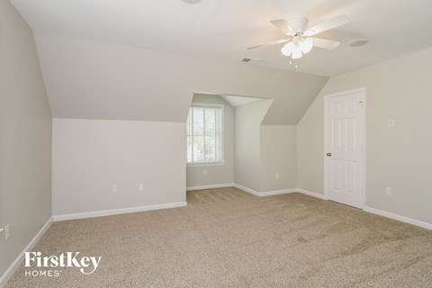 the spacious living room with ceiling fan and carpeting