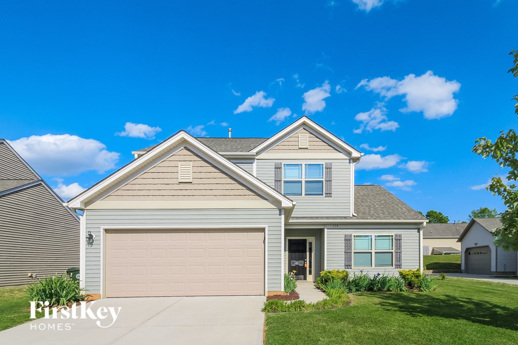 a beige house with a garage door and a blue sky