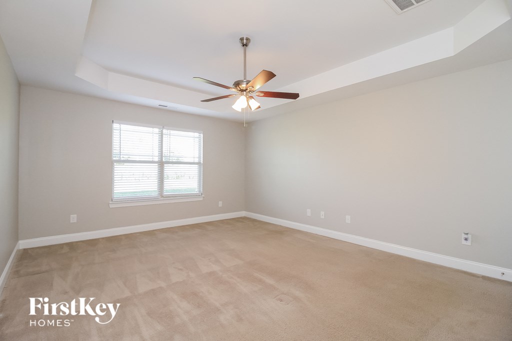 the spacious living room with ceiling fan and carpeting