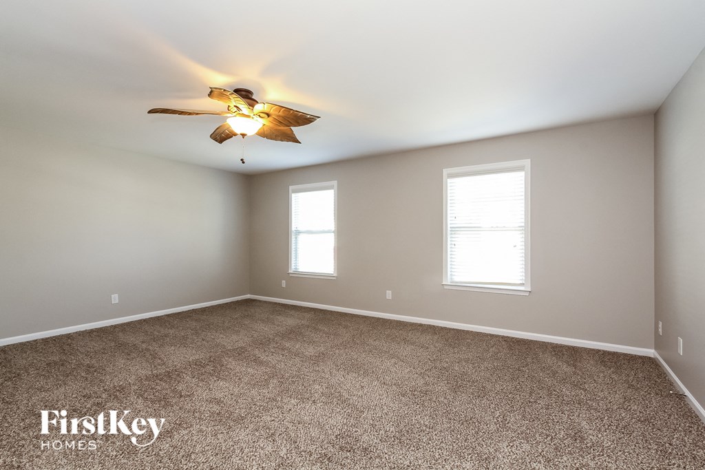 a bedroom with carpet and a ceiling fan and two windows