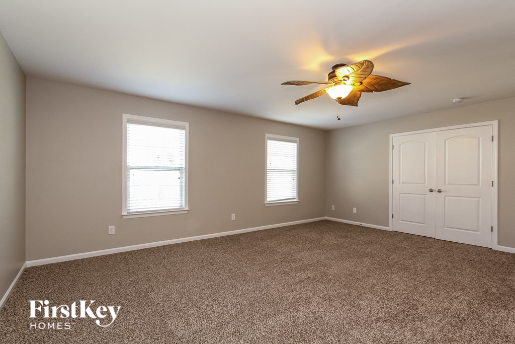 the master bedroom has a ceiling fan and a carpeted floor