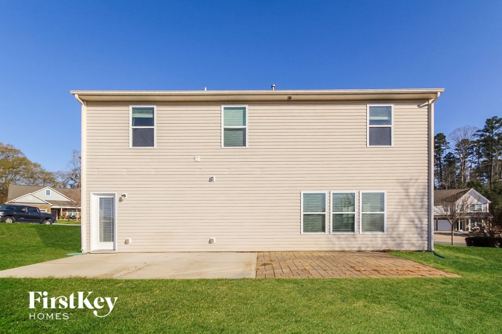 a small house with tan siding and green grass