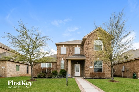 A brick house with a white door and windows is for sale.