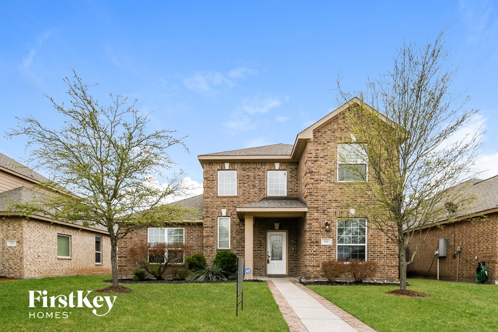 A brick house with a white door and windows is for sale.