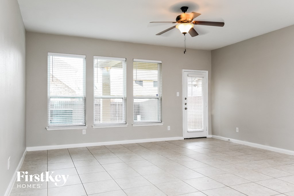 A spacious room with a ceiling fan and three windows.