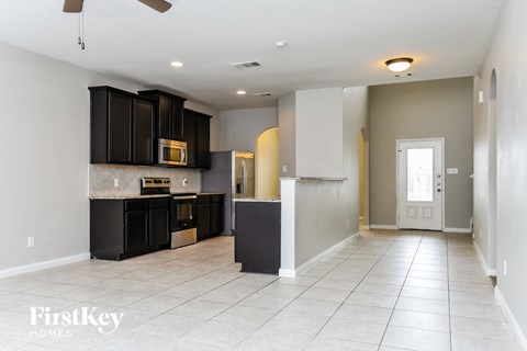 A spacious kitchen with dark brown cabinets and a white ceiling fan.