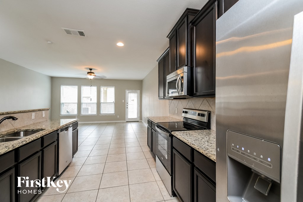 A kitchen with black cabinets and a stainless steel refrigerator.