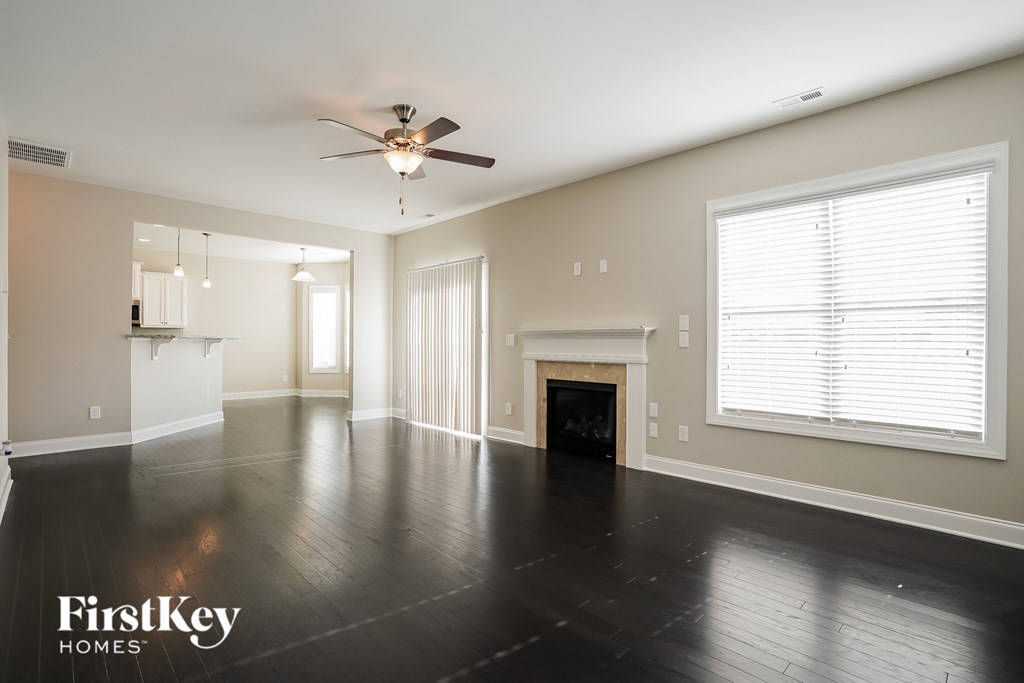 an empty living room with a ceiling fan and a fireplace