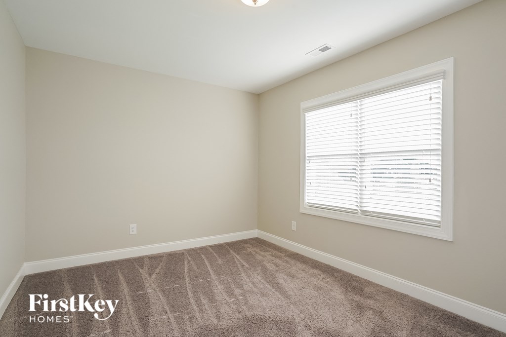 a bedroom with carpet and a large window
