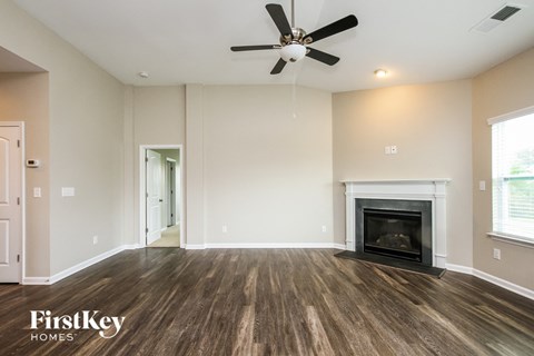 A spacious room with a fireplace and a ceiling fan.