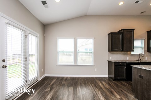 A kitchen with a black counter top and wooden floors.