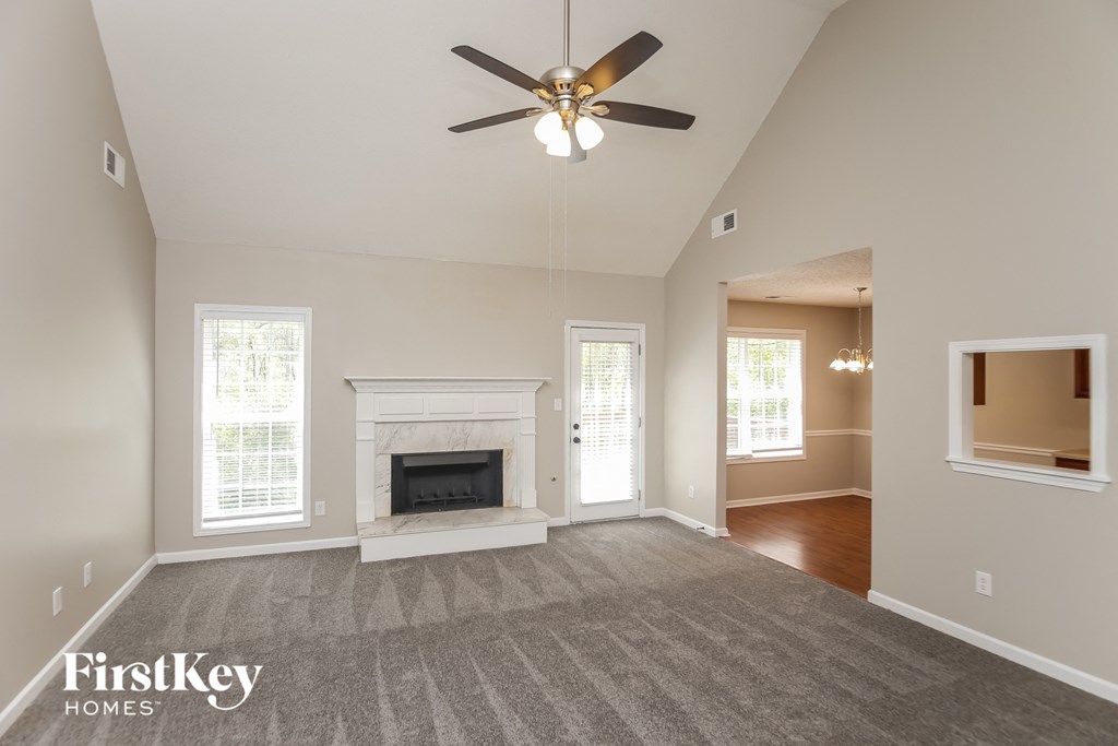 A spacious living room with a fireplace and a ceiling fan.
