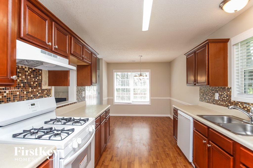 A kitchen with wooden cabinets and a white stove top oven.