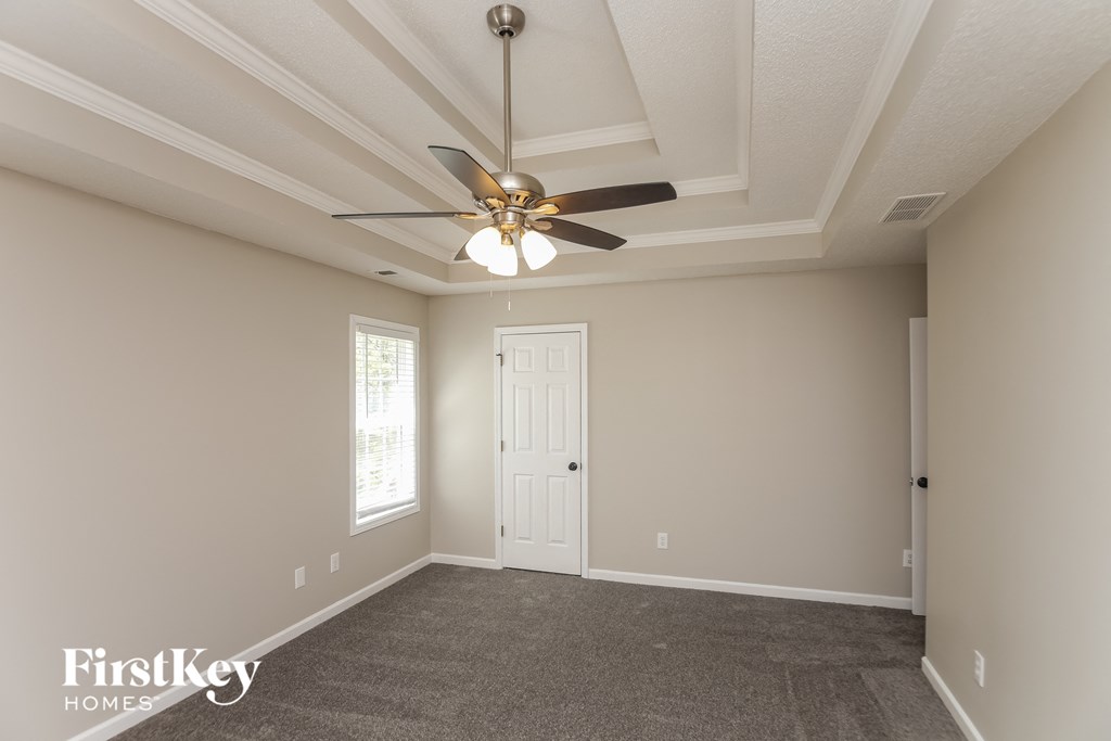 A spacious room with a ceiling fan and carpeted floor.