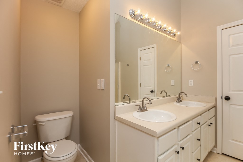 A bathroom with a toilet, sink, and mirror.