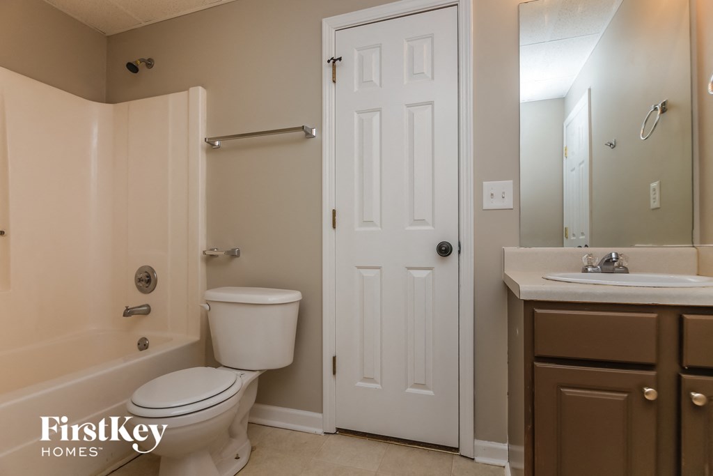 A bathroom with a toilet, sink, and mirror.