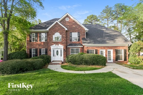 a brick house with a white front door and a lawn