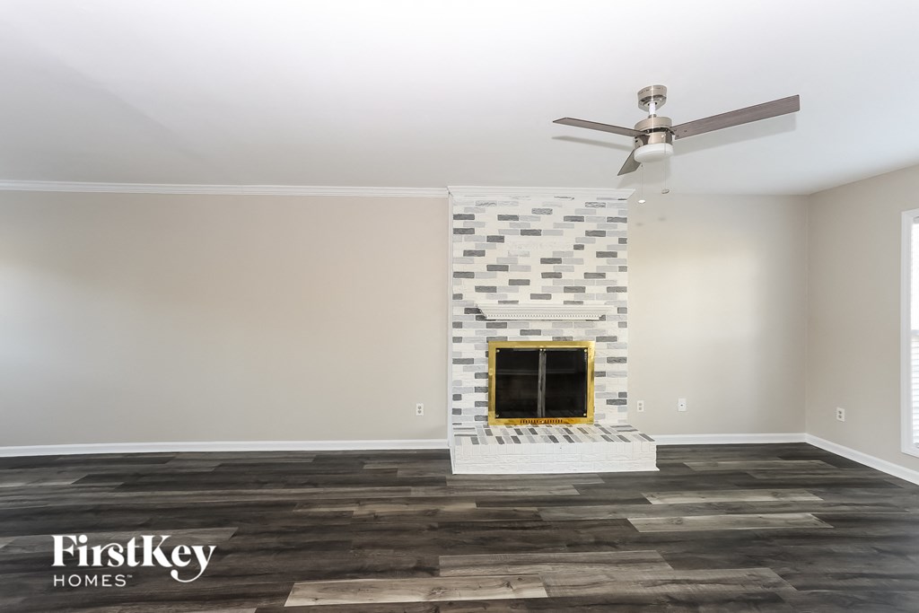 the living room of a new home with a brick fireplace and a ceiling fan