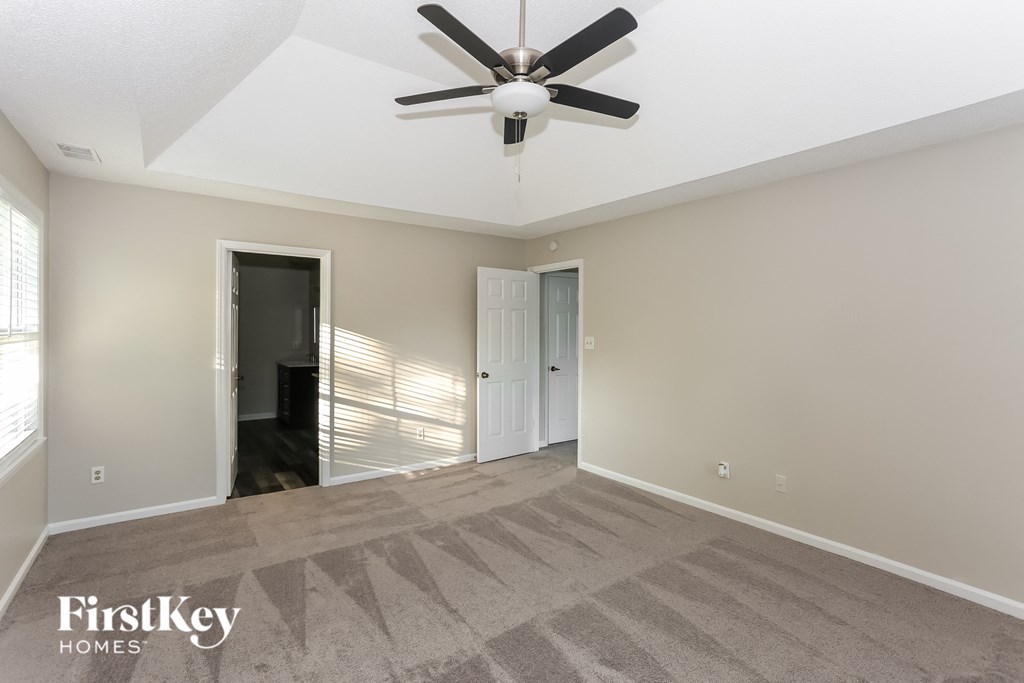 an empty living room with a ceiling fan and a door to a closet