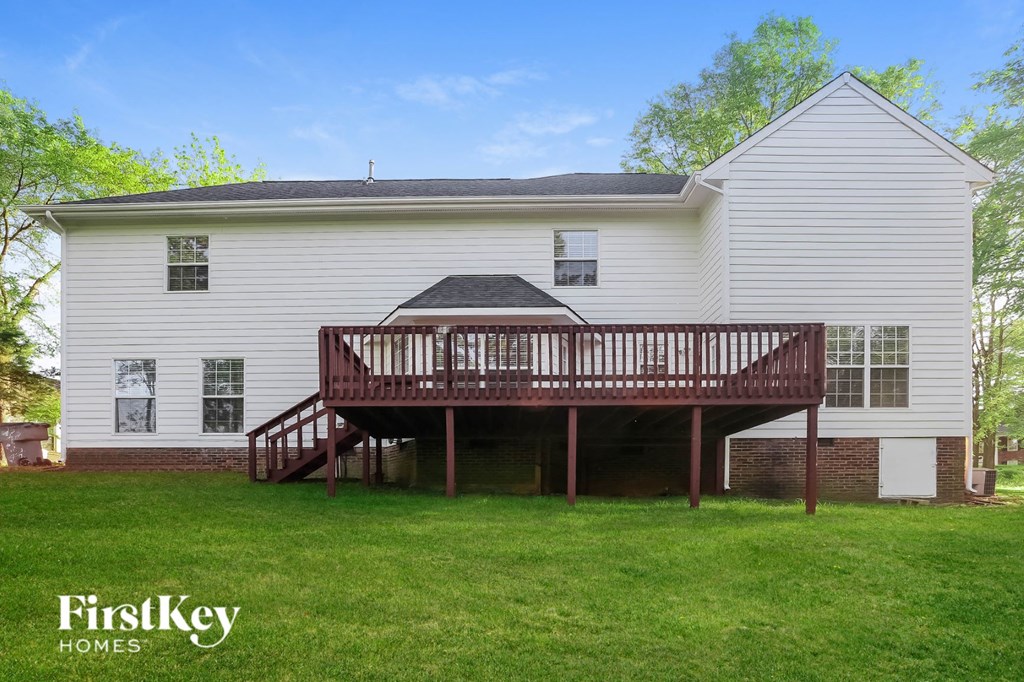 the back of a white house with a wooden deck