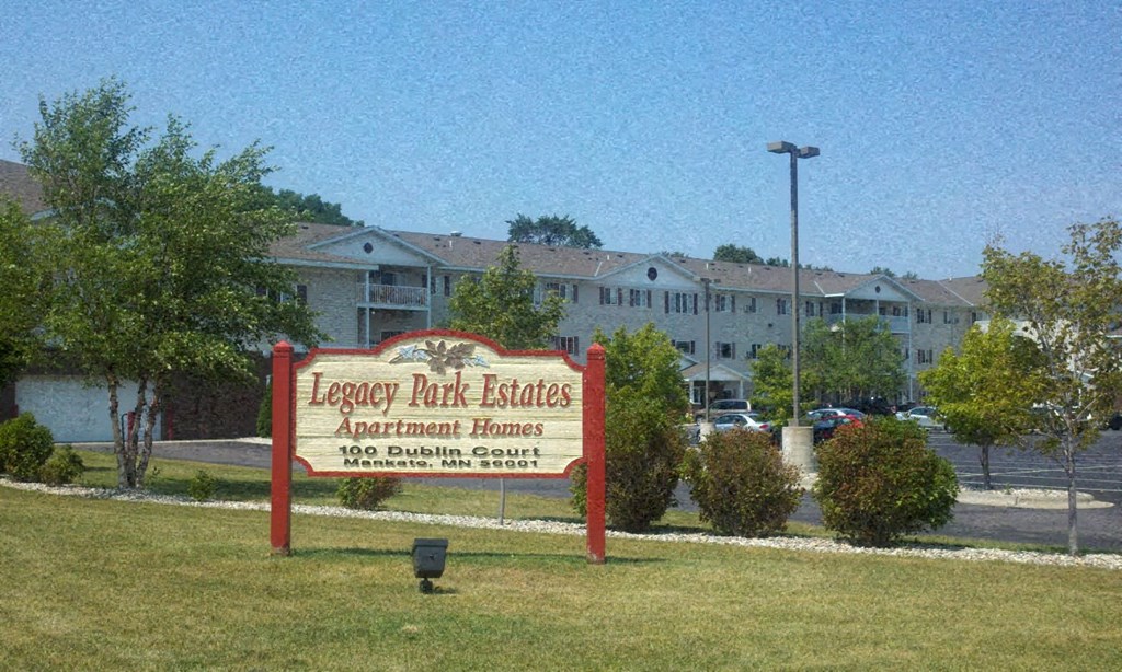 a sign for legacy park estates apartment homes with a building in the background