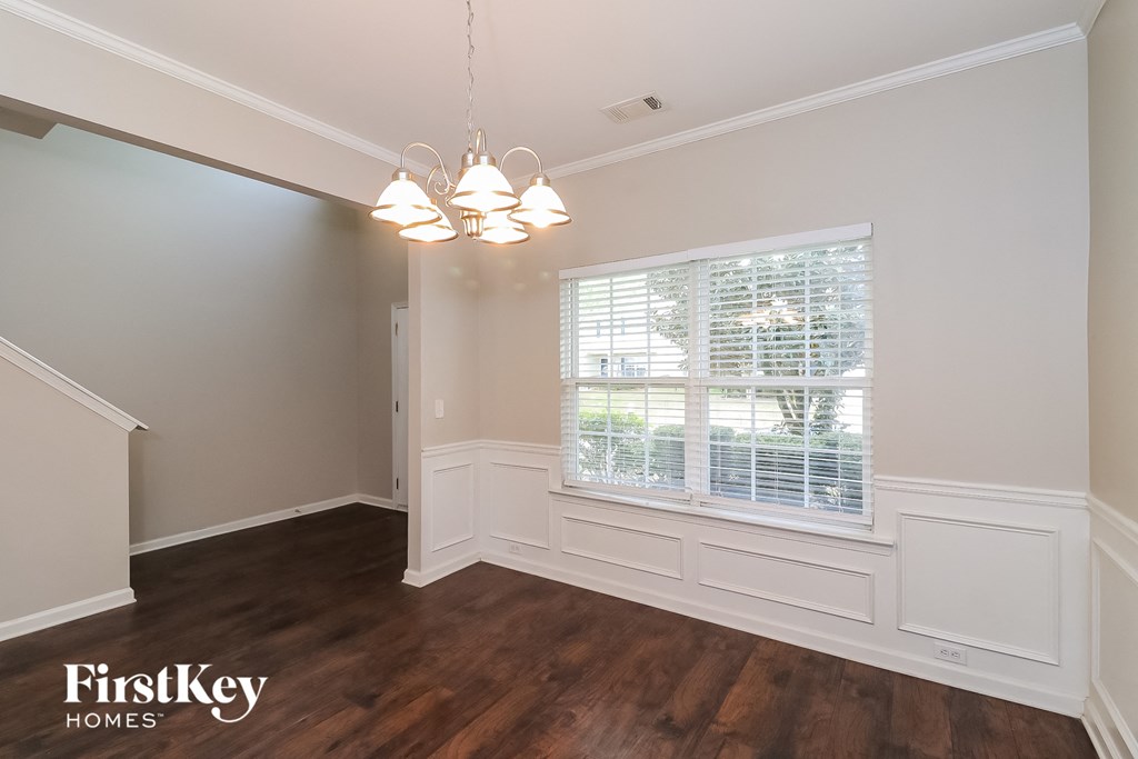 A well-lit room with wooden floors and a window with blinds.