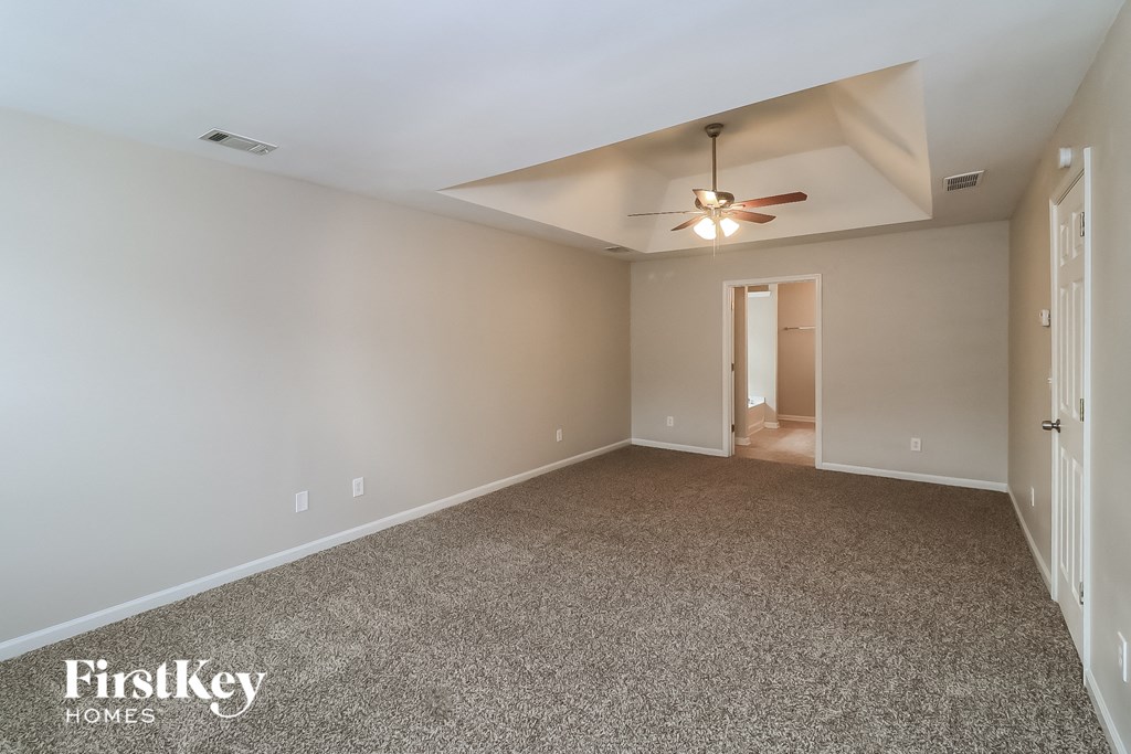 A spacious room with a ceiling fan and a carpeted floor.