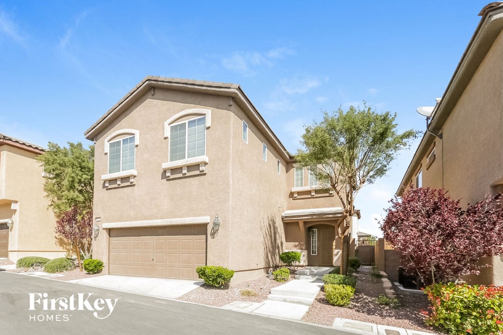 a beige house with a garage door and a sidewalk