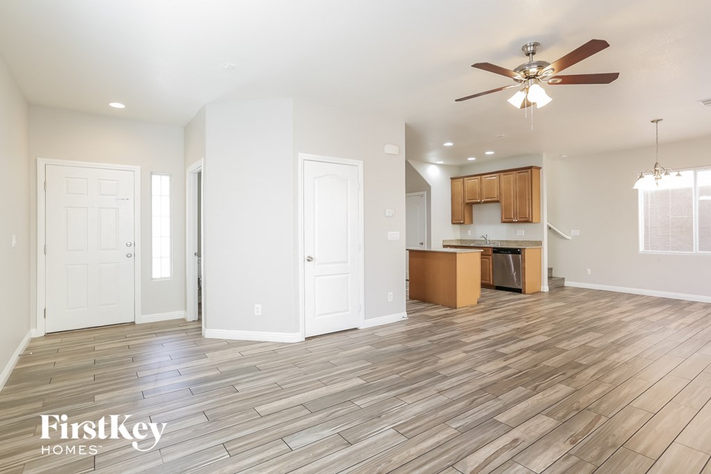 a living room and kitchen with wood flooring and a ceiling fan