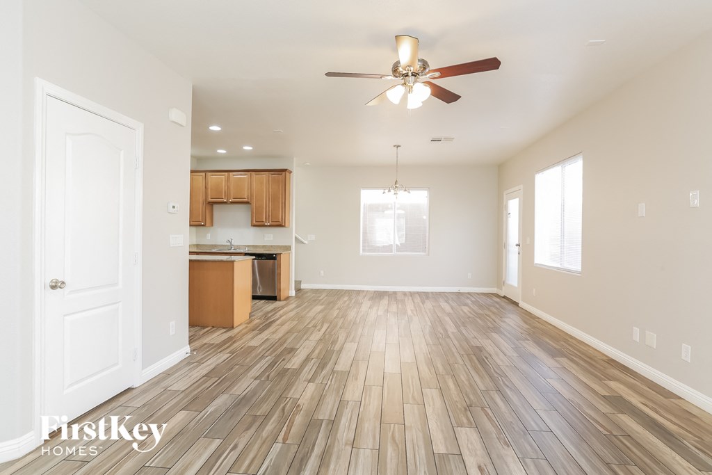 a living room and kitchen with wood flooring and a ceiling fan