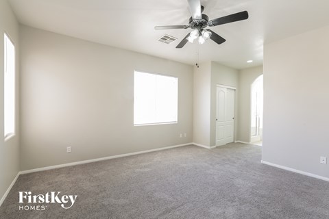 a spacious living room with carpet and a ceiling fan