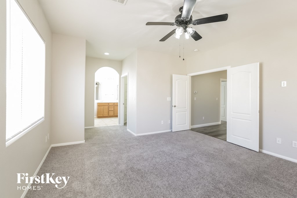 a spacious living room with carpet and a ceiling fan