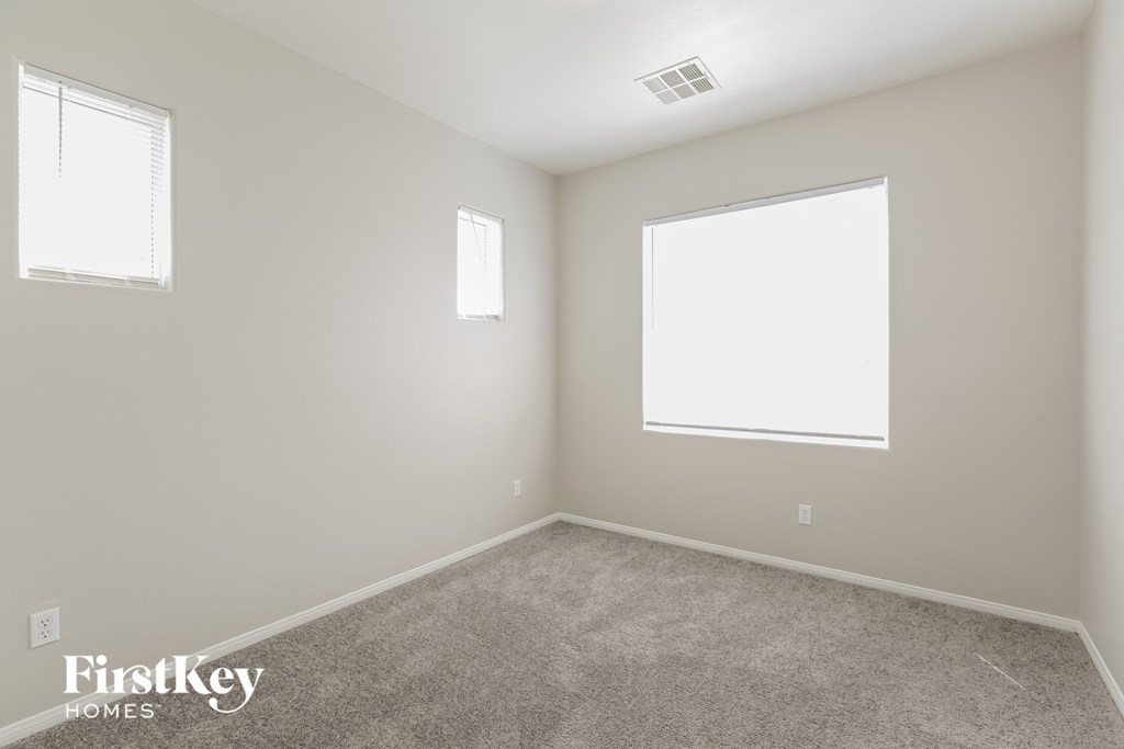 a bedroom with two windows and a carpeted floor