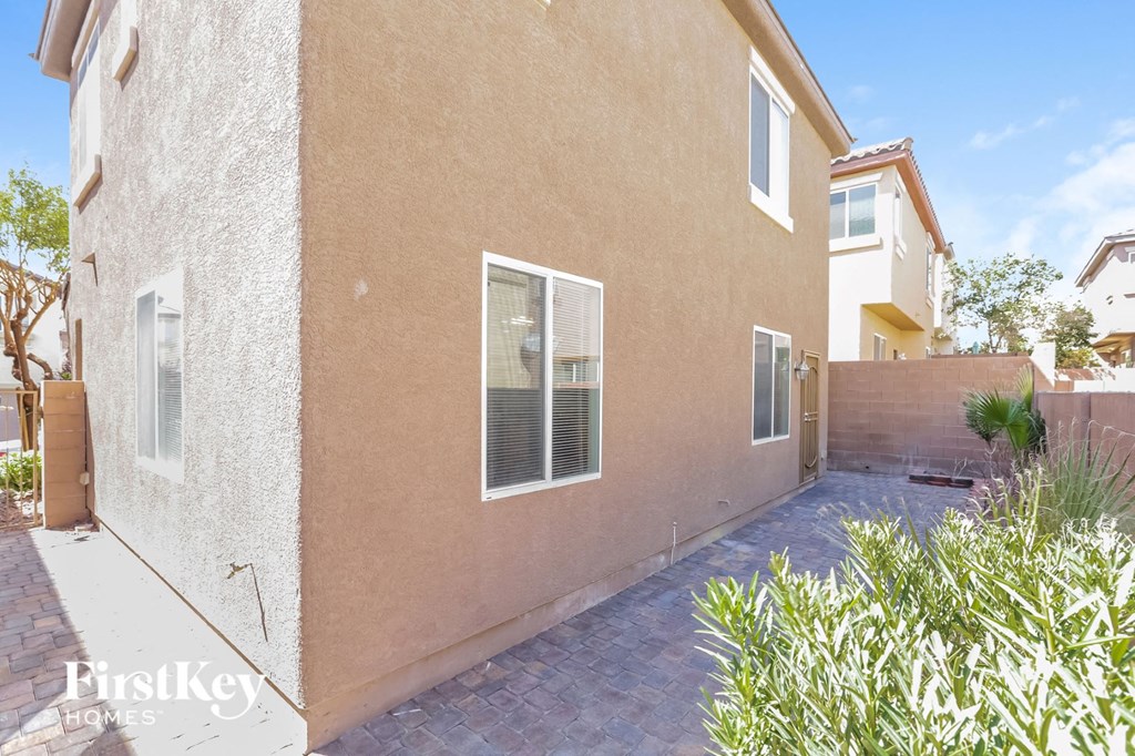 a side view of a beige house with a walkway and plants